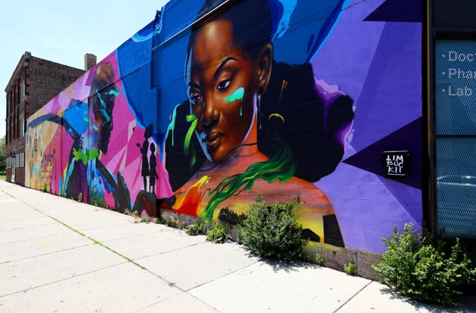 A mural of a woman by Max Sansing is displayed on the side of building in Chicago