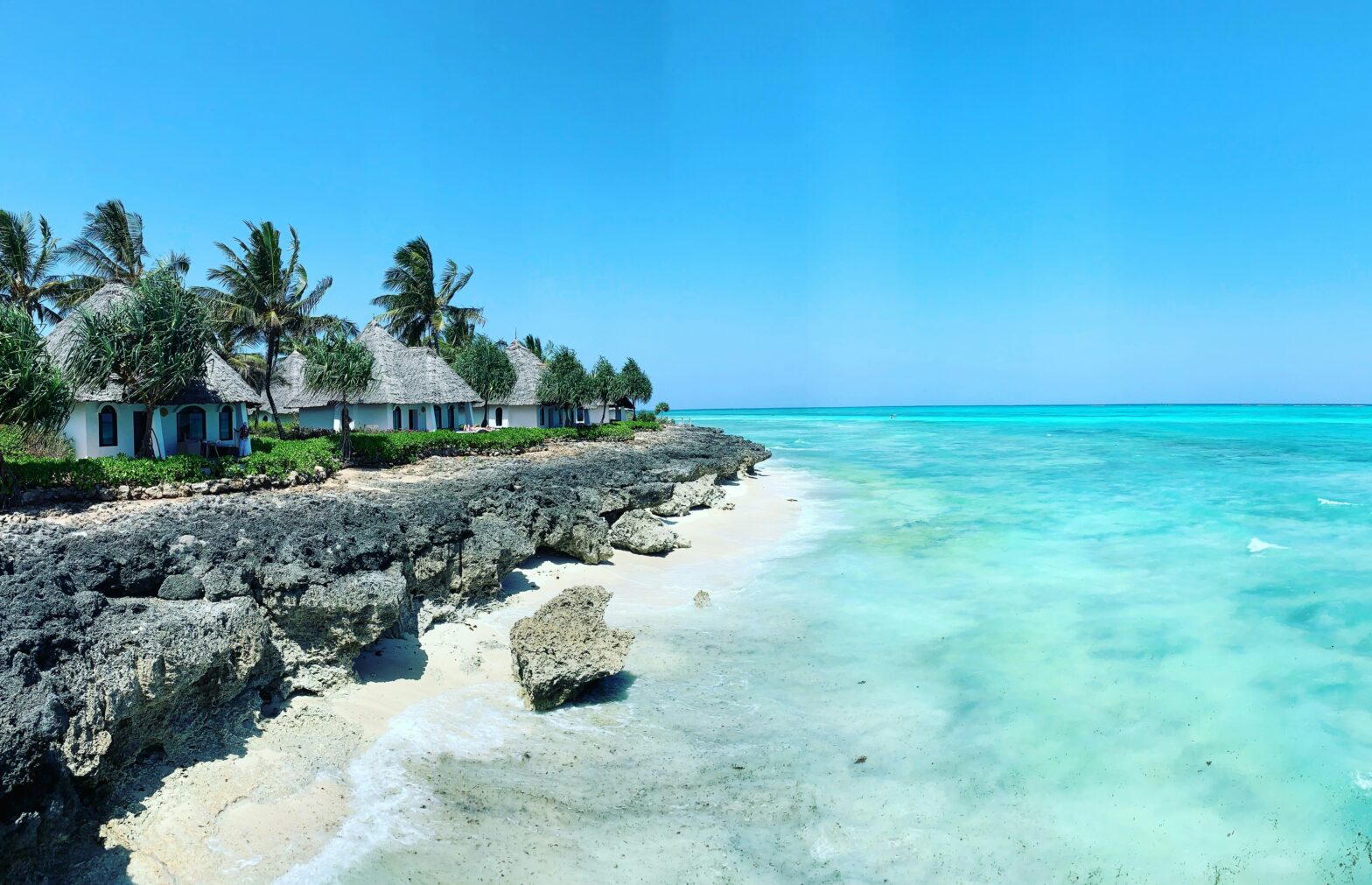 gray roof huts on a rocky coastal shoreline of white sand beaches of Zanzibar, Tanzania