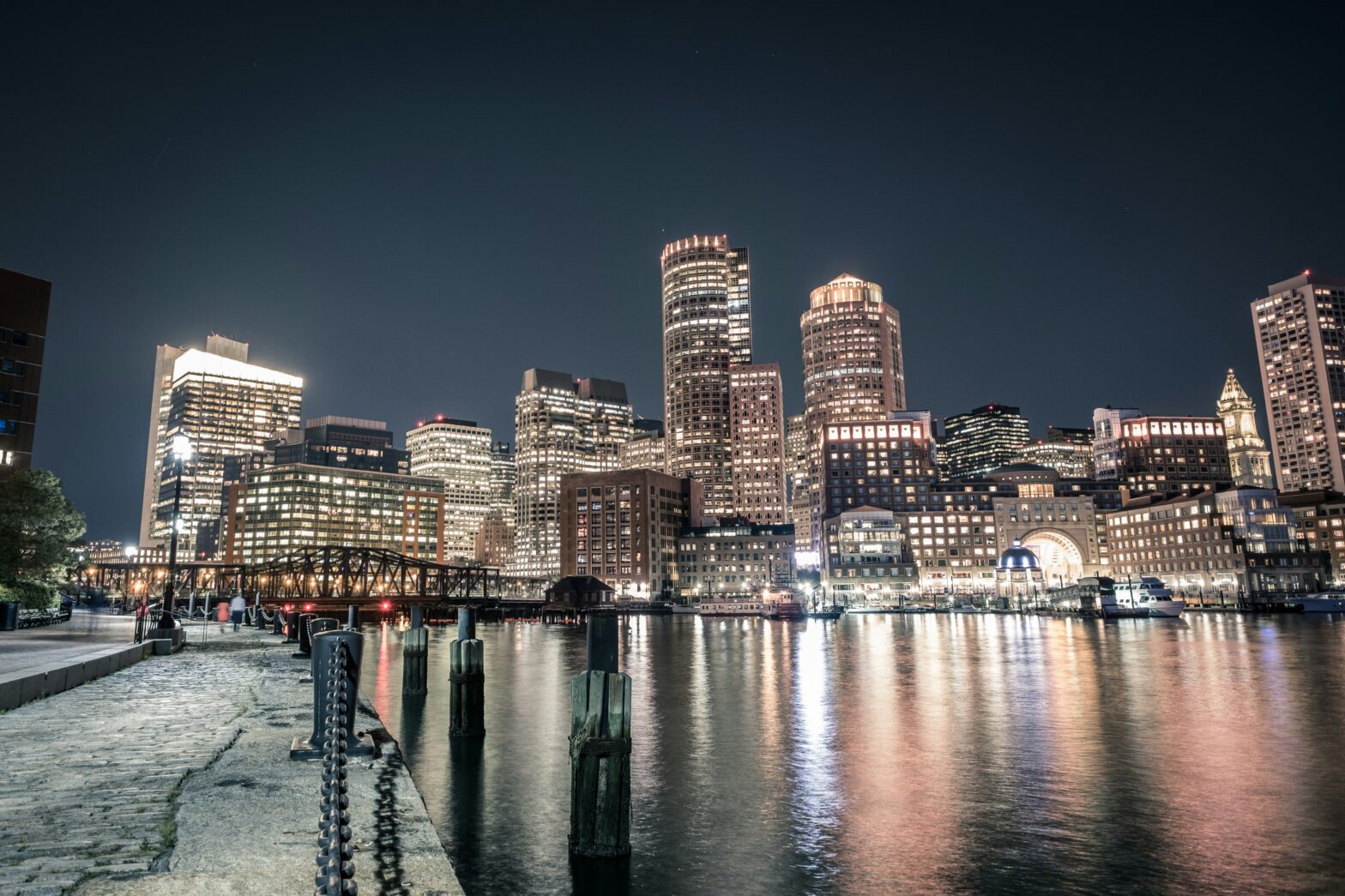 Boston skyline illuminated at night, with lights reflecting off the Charles River.