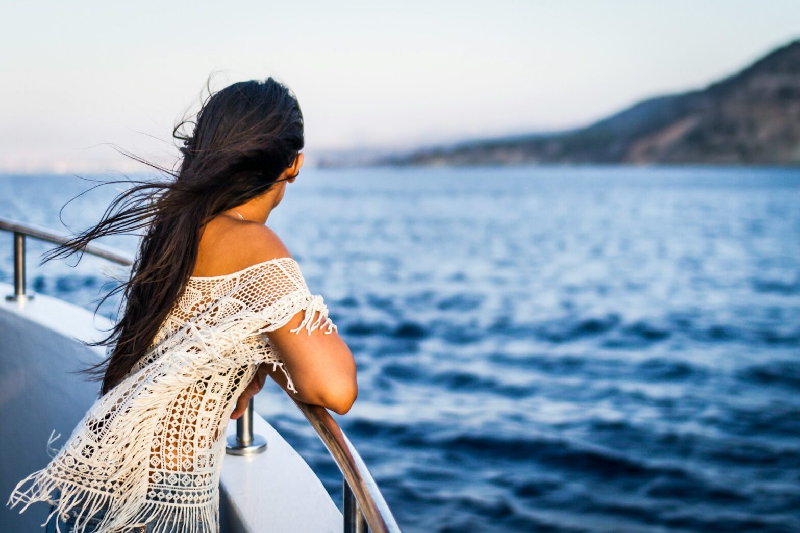 Woman's head is turned while looking at ocean on a boat