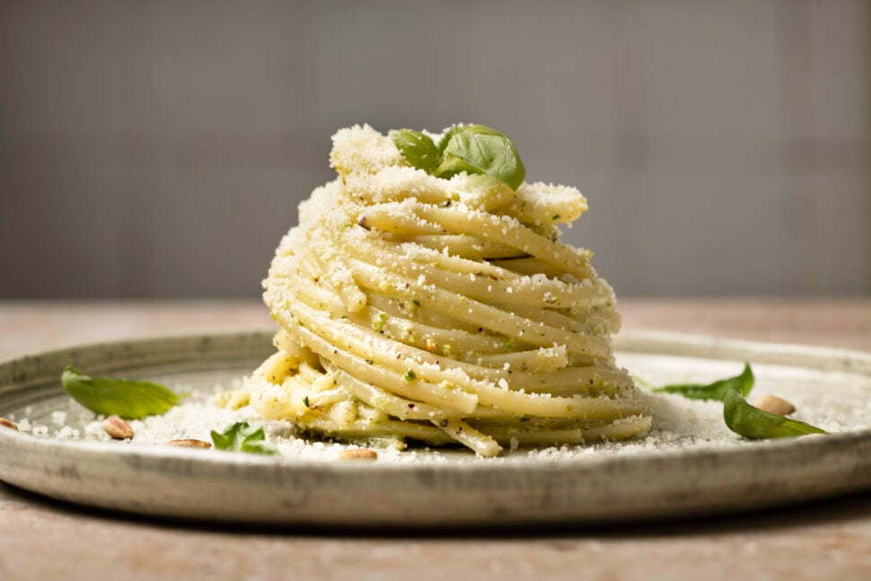 Linguine pasta on plate with pesto and basil garnished with parmesan and pine nuts. copy space, studio shot made with Nikon equipment