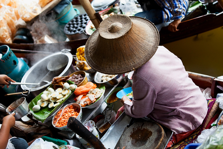 Lady is selling traditional thai food from her boat.