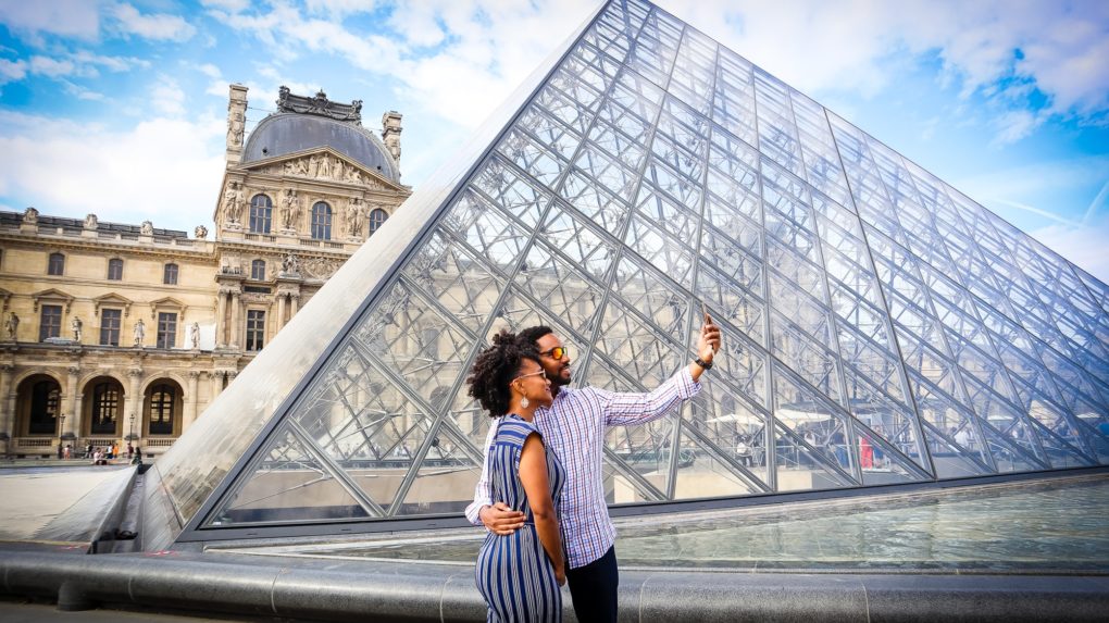 two people taking picture at the Louvre in Paris