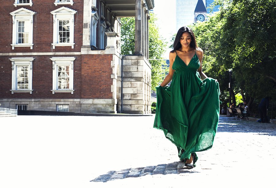 Woman walking down street in green flowing dress.