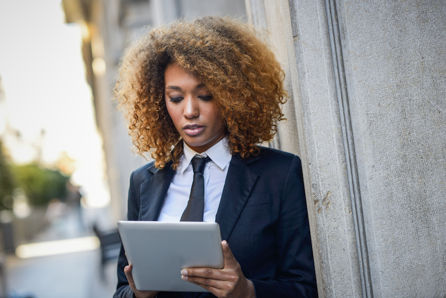 Black woman using tablet computer in town