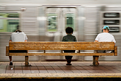 Three people, two men and one woman, waiting for their subway train in 125 st. station in New York City - Fastest Way to Reach JFK from Manhattan