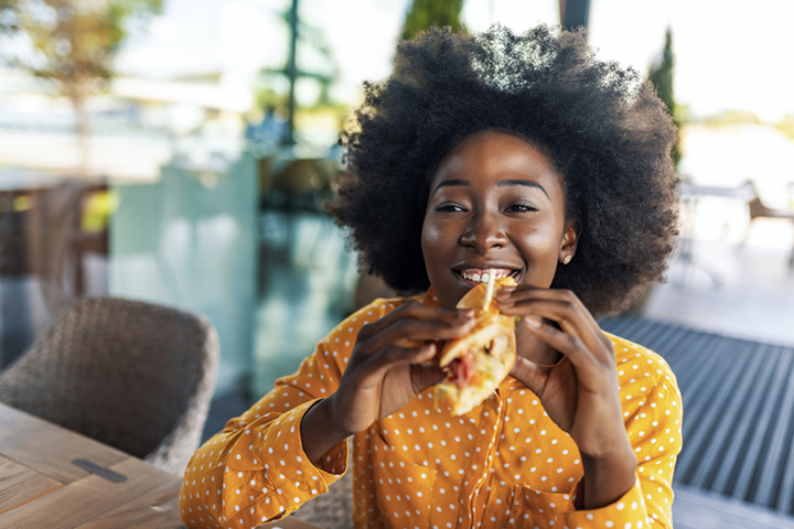 woman eating a sandwich and smiling at a restaurant