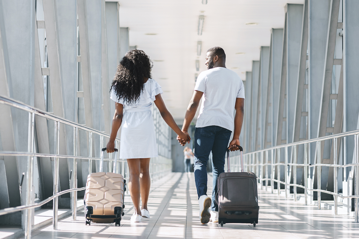 couple traveling through airport with luggage in bag / luggage weighers