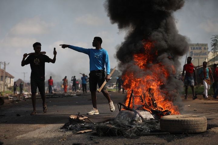 two boys standing by a fire in the street