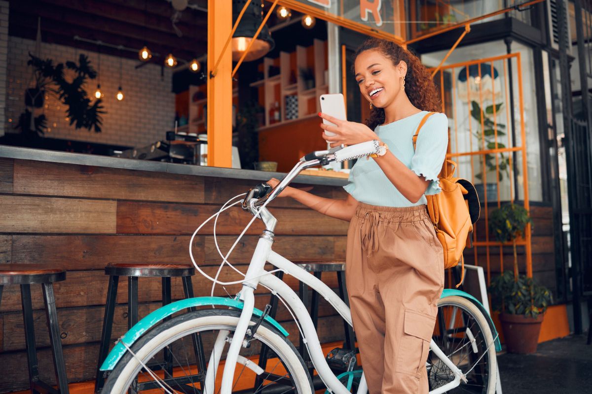 woman smiling while holding bike and phone outside of a cafe in San Francisco