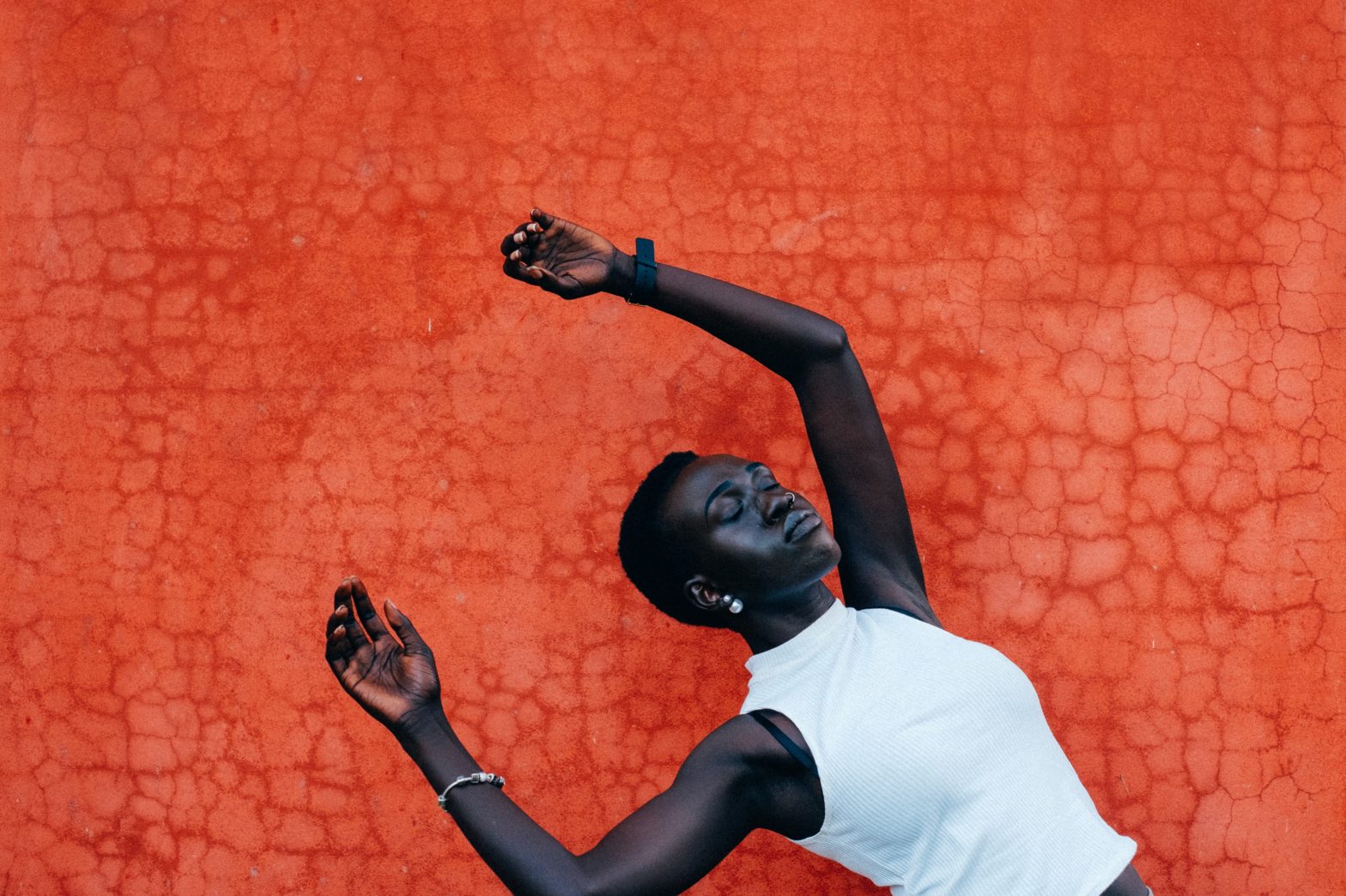 black woman wearing white sleeveless shirt against orange background