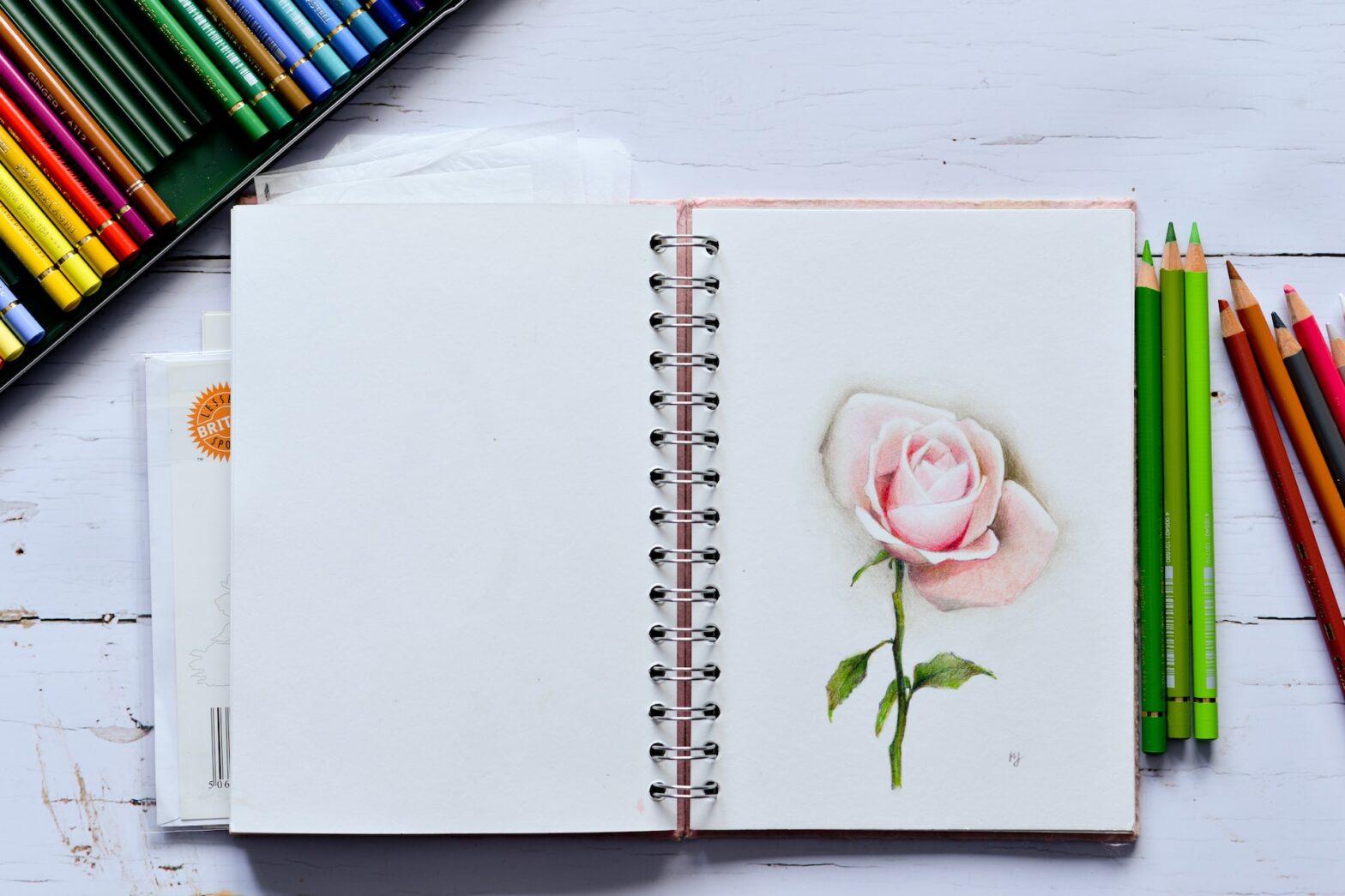 journal with flower sketched on notepad next to colored pencils and markers