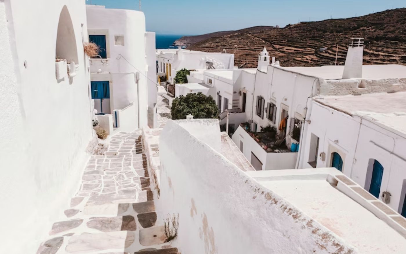 row of white buildings with hills and beach off in the distance in the hidden gem of Greece, Sifnos