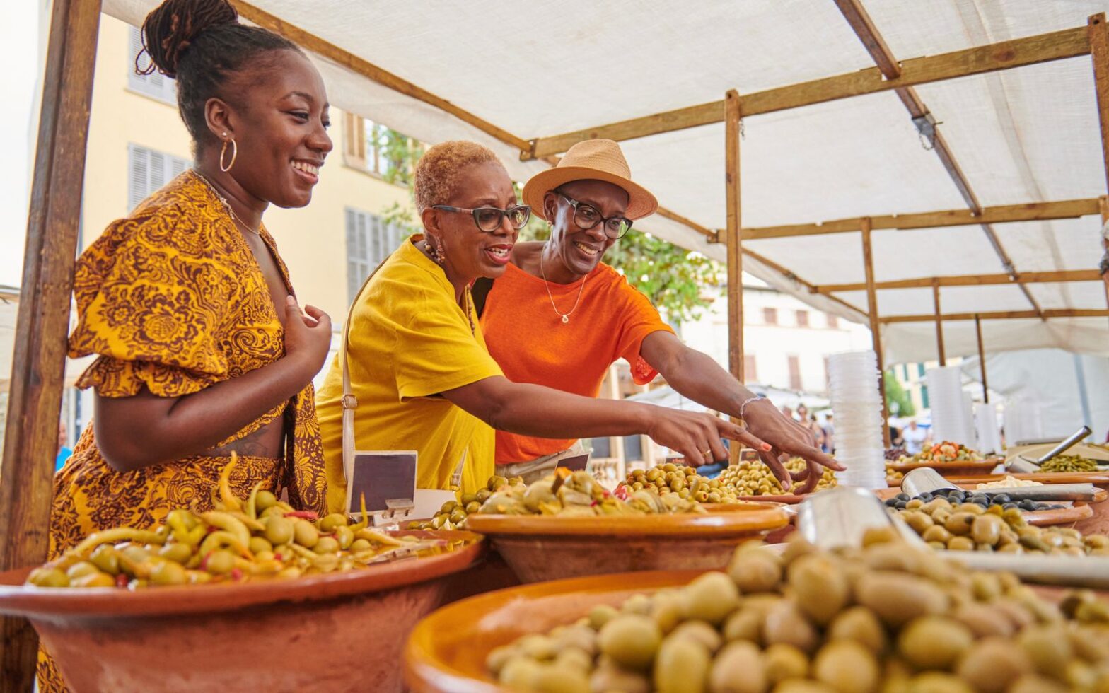 three black women looking at vegetables at a farmers market - Tour Companies that Teach Black history