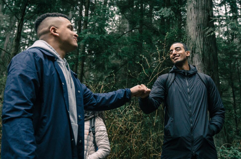 two men fistbumping while hiking in the woods