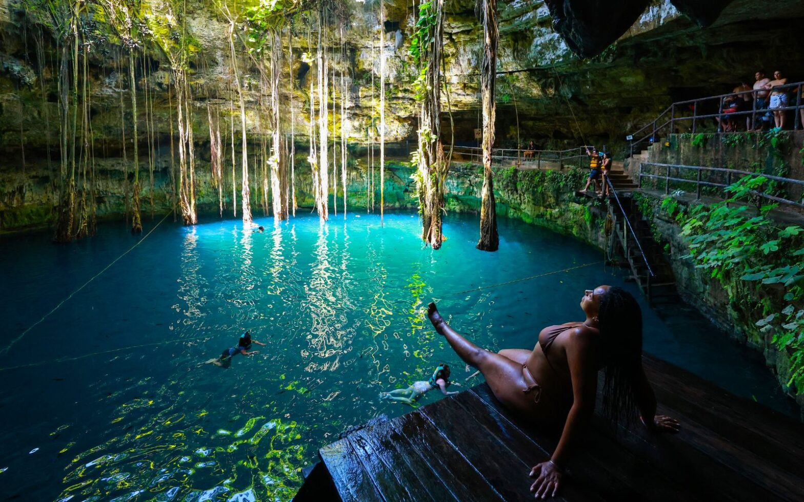 Black woman sitting on the edge of cenote azul