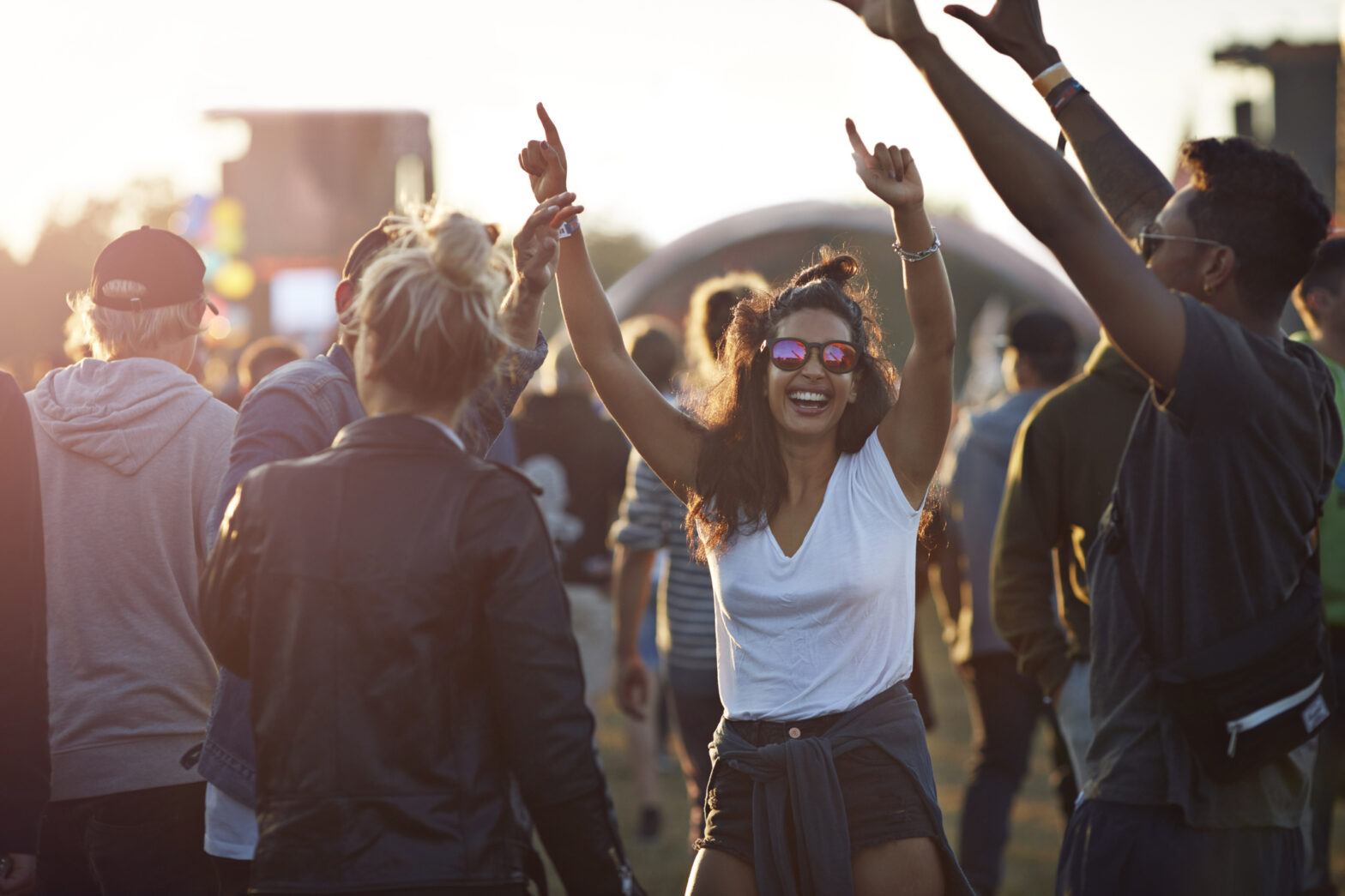 Friends hanging out at big music festival, at sunset