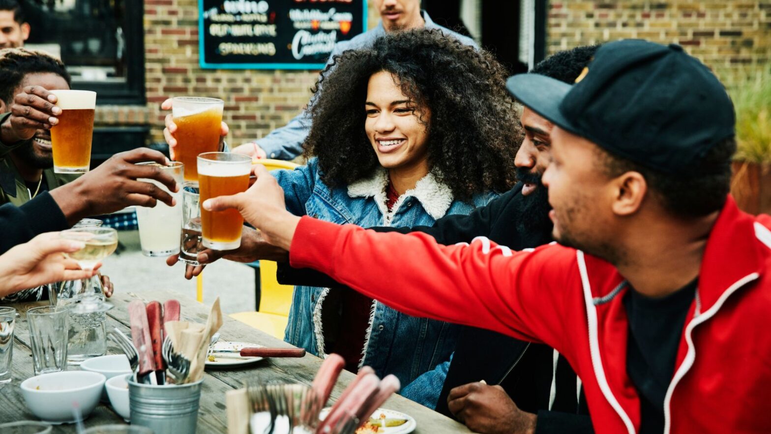 group of people toasting with beers at an outdoor restaurant