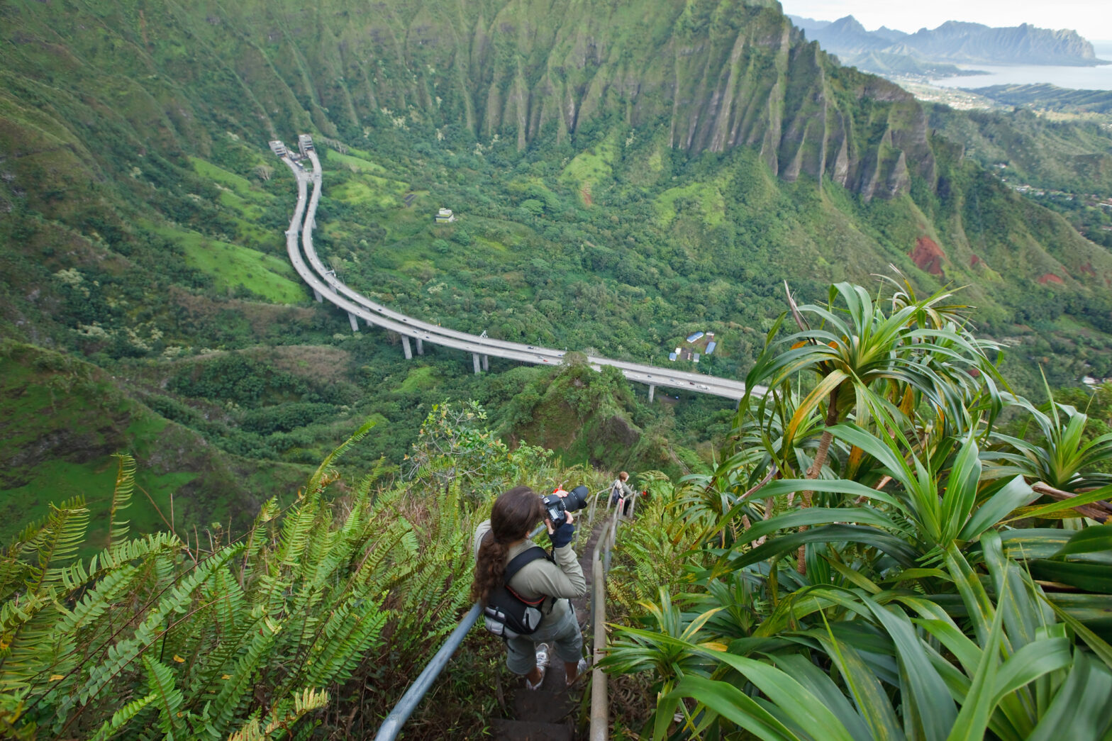 The hike up the Stairway to Heaven is also known as Haiku Stairs. It is one of the most popular trails in Oahu young woman taking photo.