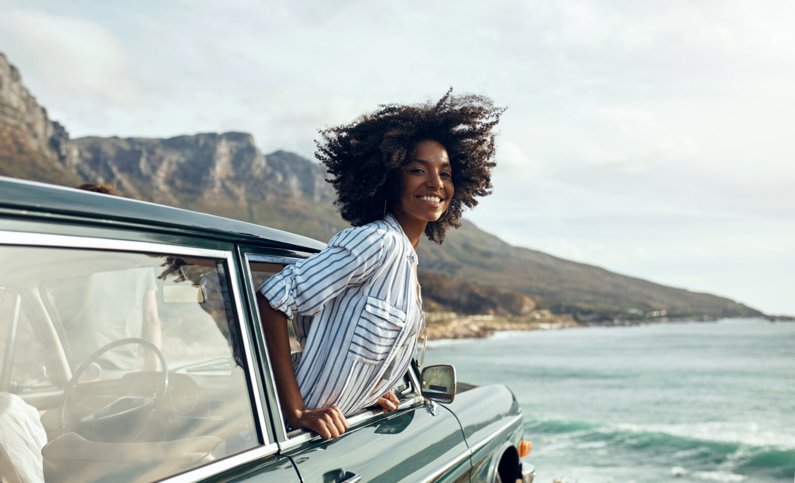 Travel Noire Awards 2023. Shot of a happy young woman leaning out of car window on a road trip