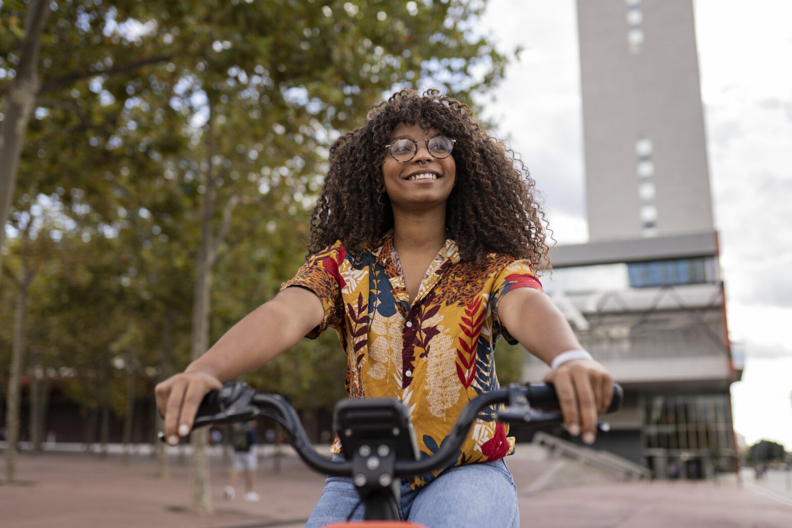 Smiling young woman riding bicycle at footpath