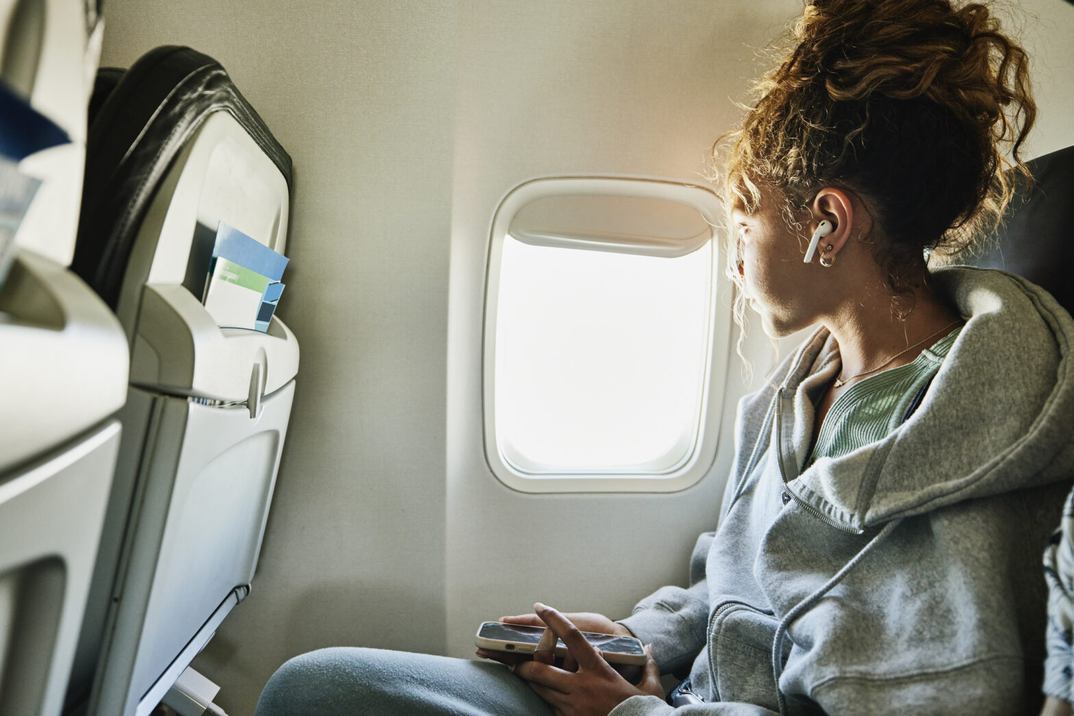 Medium shot of girl looking out window of commercial airplane while on vacation