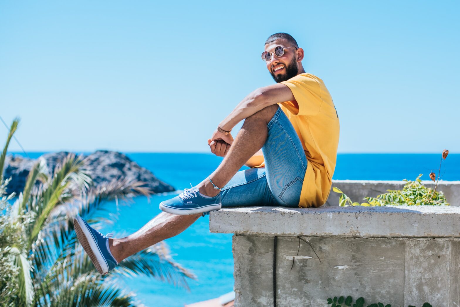 man sitting on ledge in Greek Islands