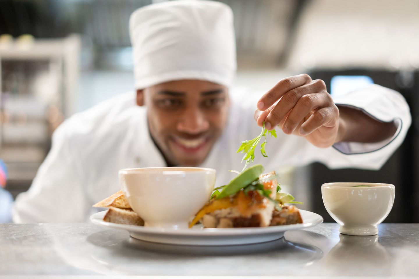 male chef decorating plate in restaurant kitchen