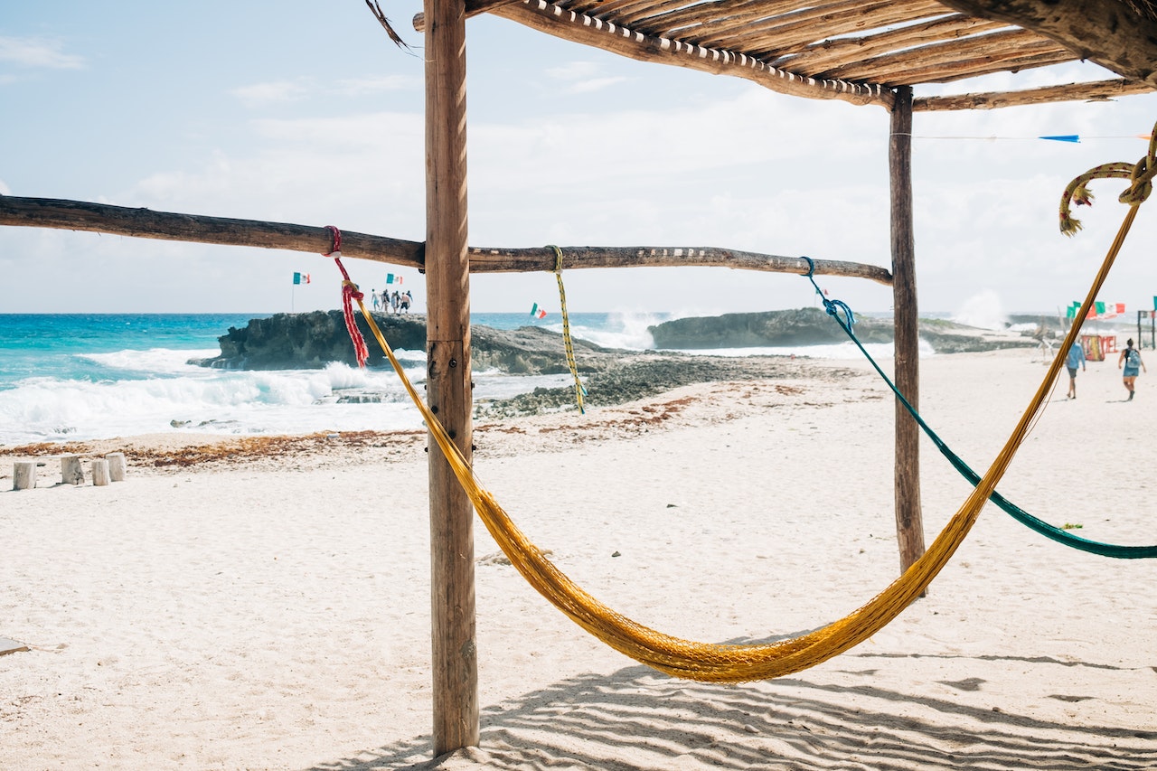 With so many things to do in Cozumel it almost feels like too many. Check out this article to help you narrow done the best activities to do on your vacation there. Pictured: A view of a a Cozumel beach and two hammocks from under a hut.