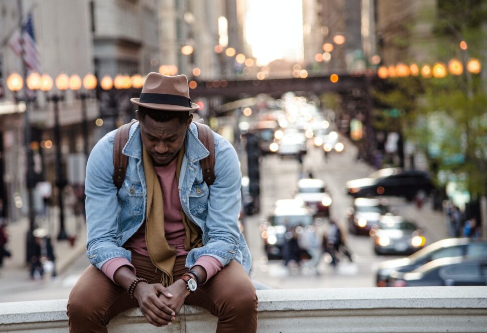 man sitting on bridge in city