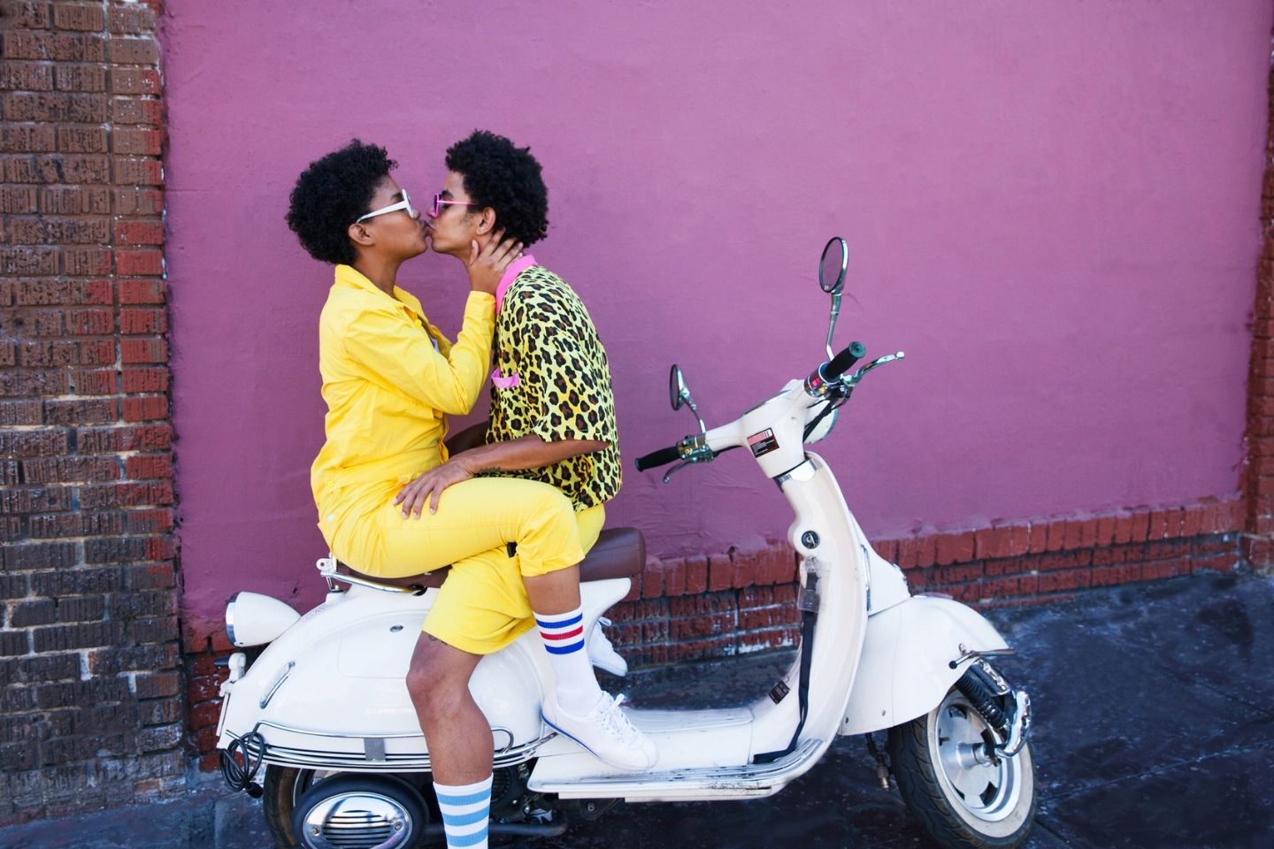 couple kissing on the back of a scooter