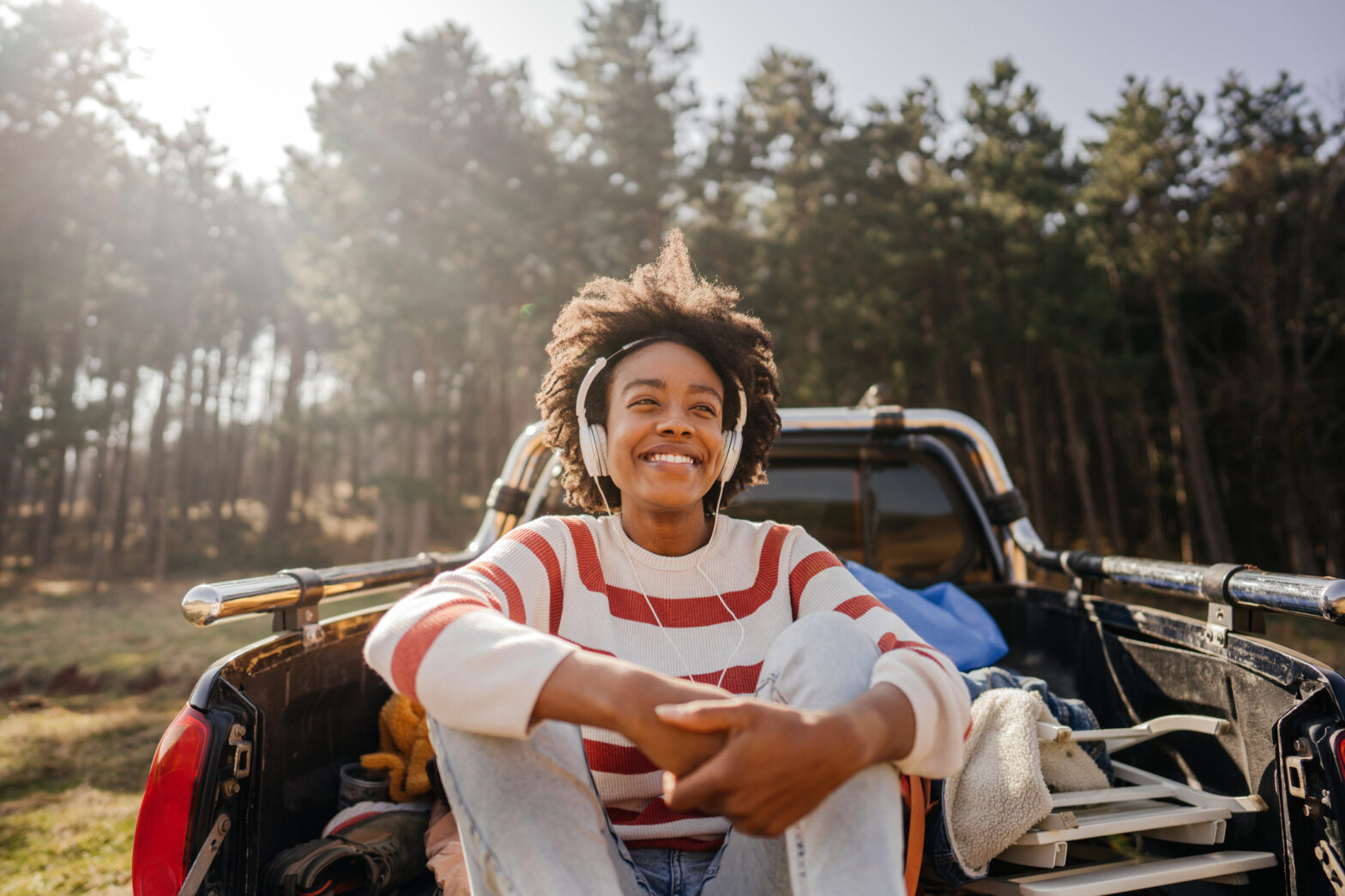 Photo of a young smiling woman listening music while on a road trip