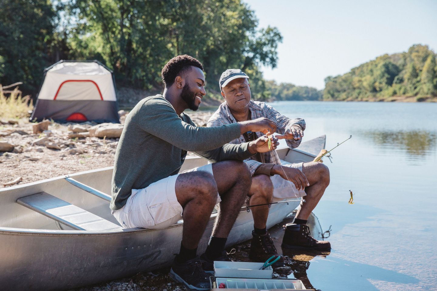 two men sitting on river fishing