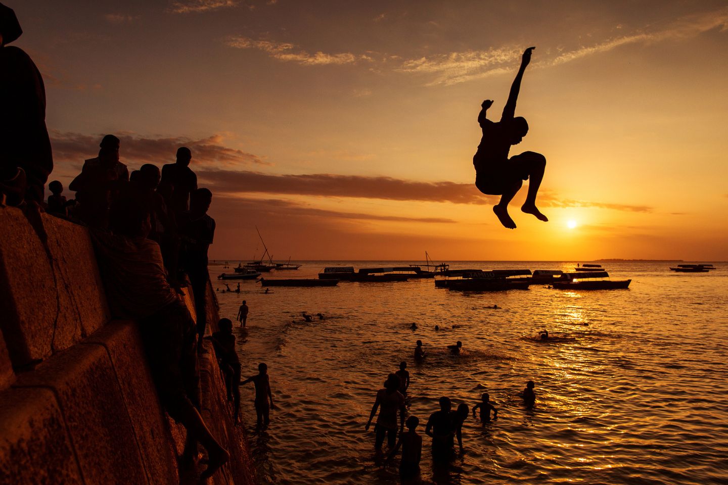 Silhouette of Happy Young boy jumping in water at sunset in Zanzibar