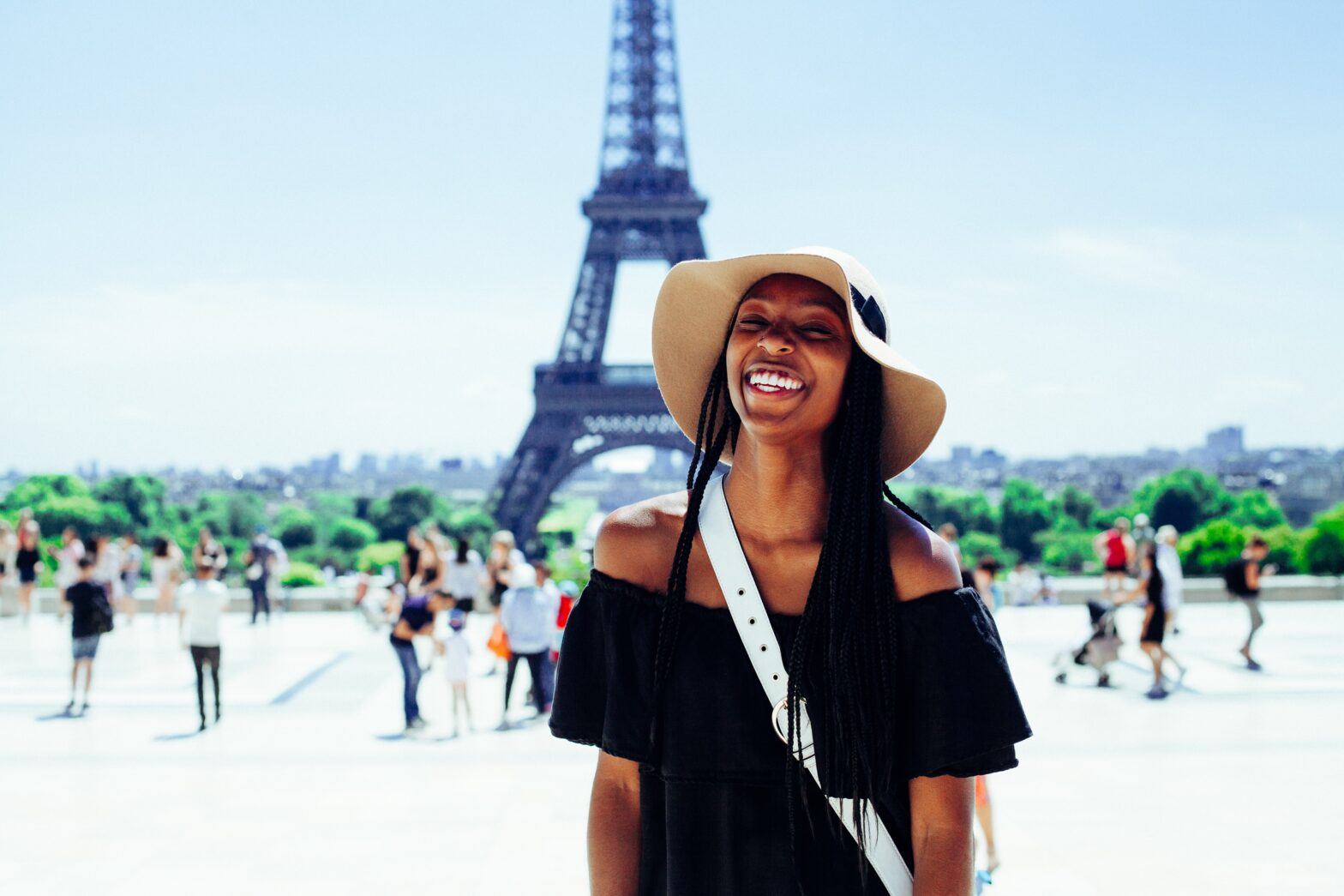 A black woman in braids smiling in front of the eiffel tower