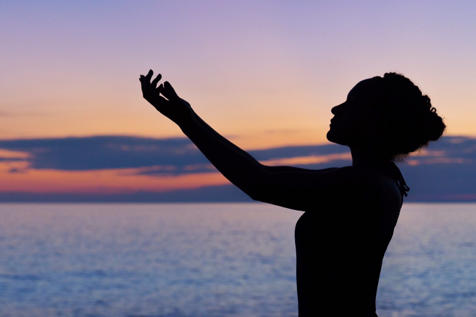 What happens at an ayahuasca retreat? Pictured: a woman at sunset with hands extended.