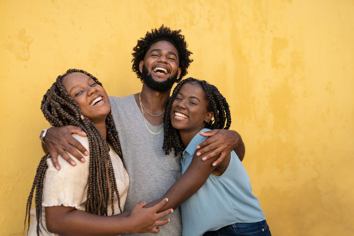 three people smiling and hugging each other