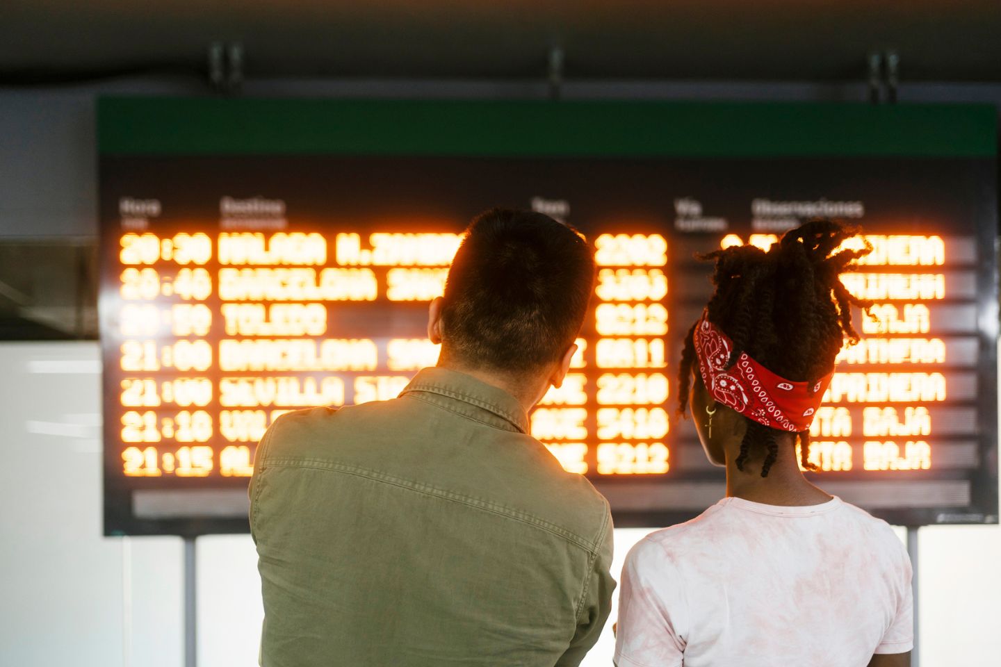 two people looking at board at the airport