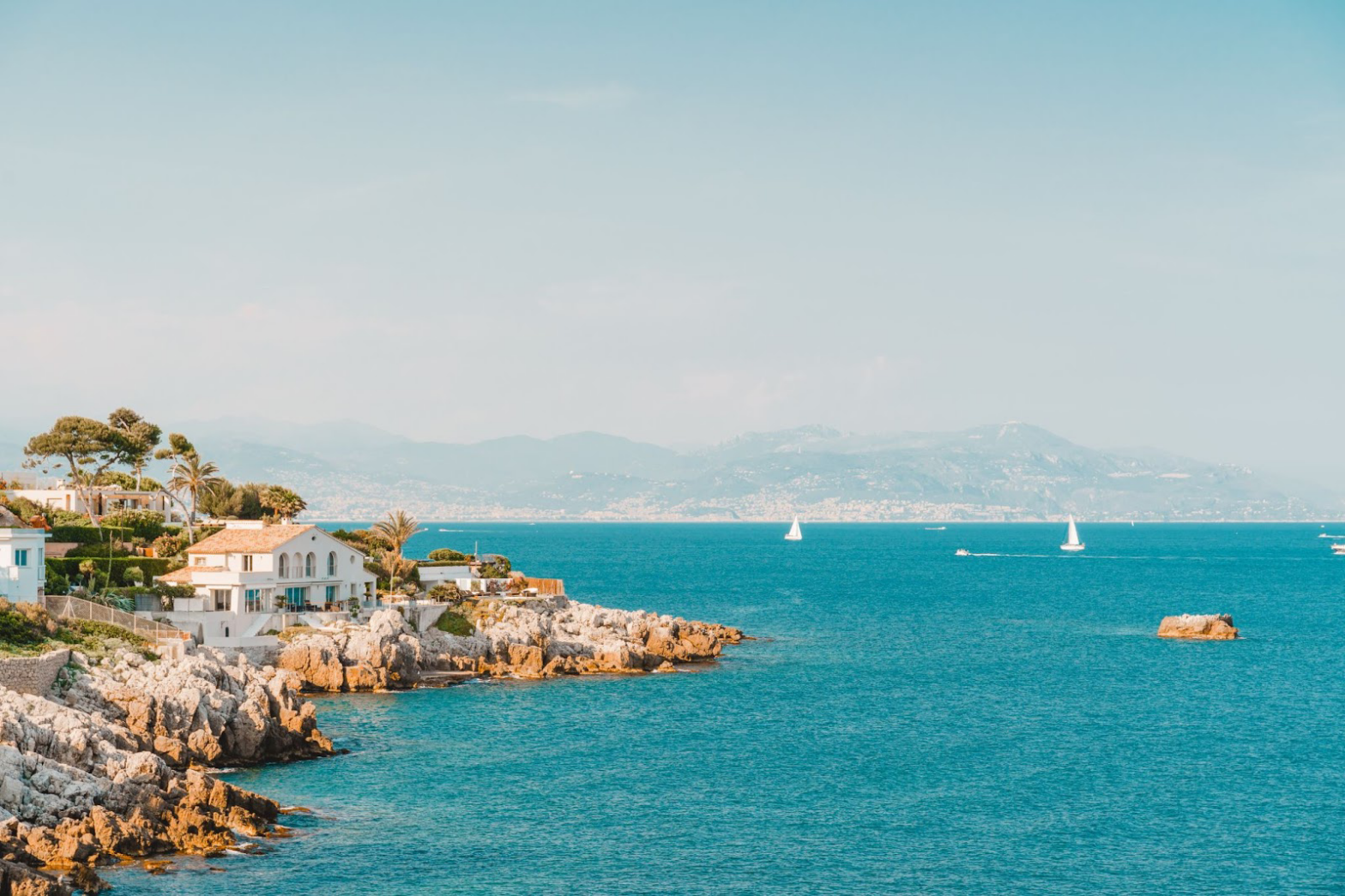 Check out these top areas in the south of France to vacation in. Pictured: a glistening coast off the south of France with idyllic homes and a calm shore