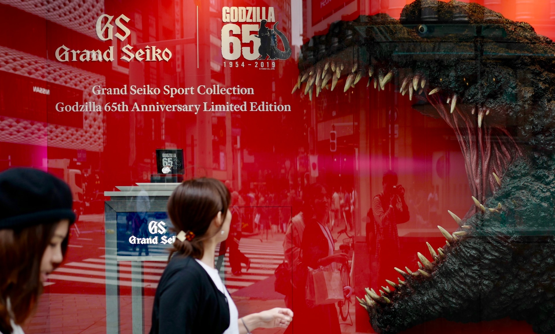 A person passing by an image of Godzilla