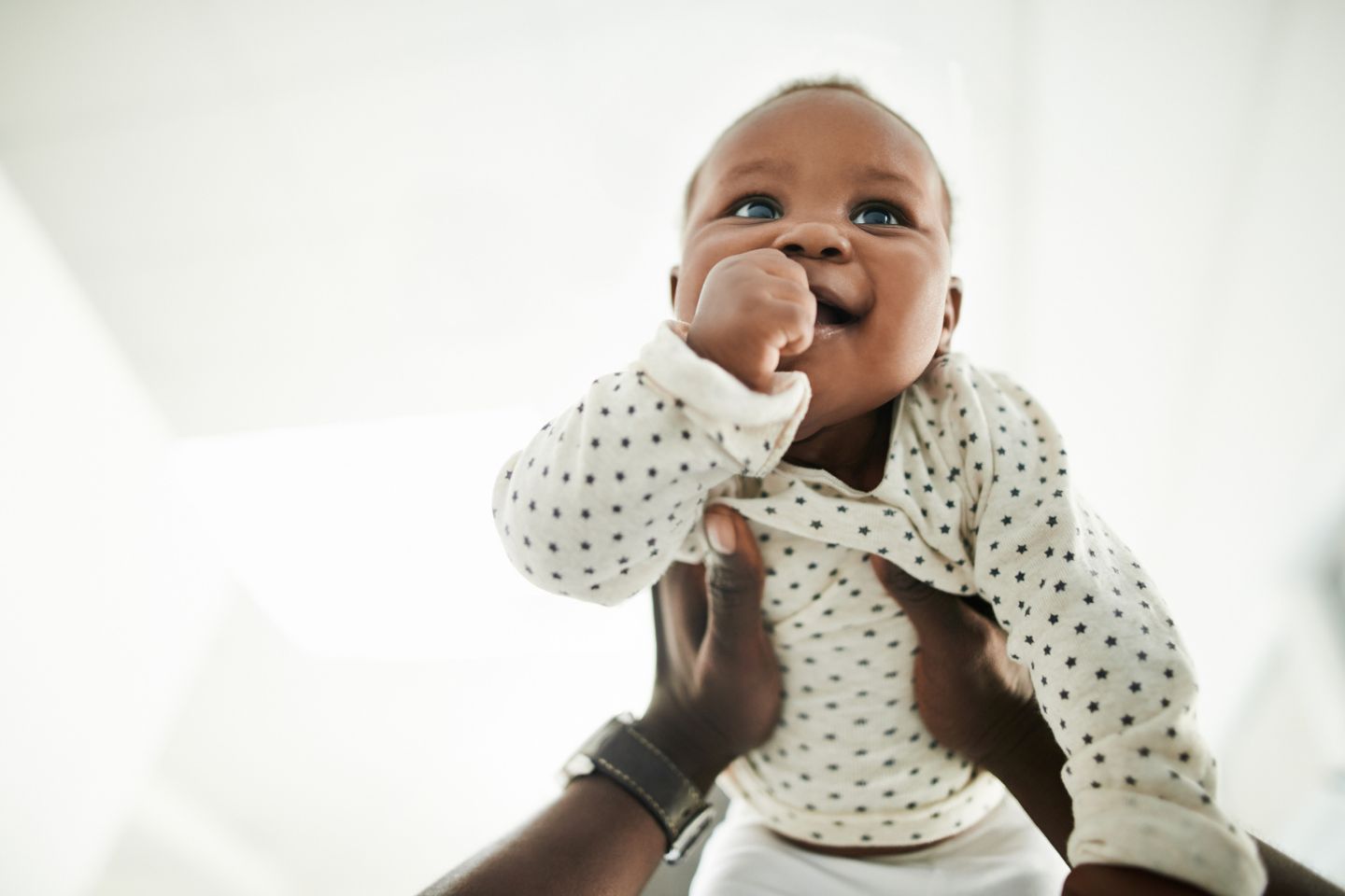 baby smiling in the air being held by father