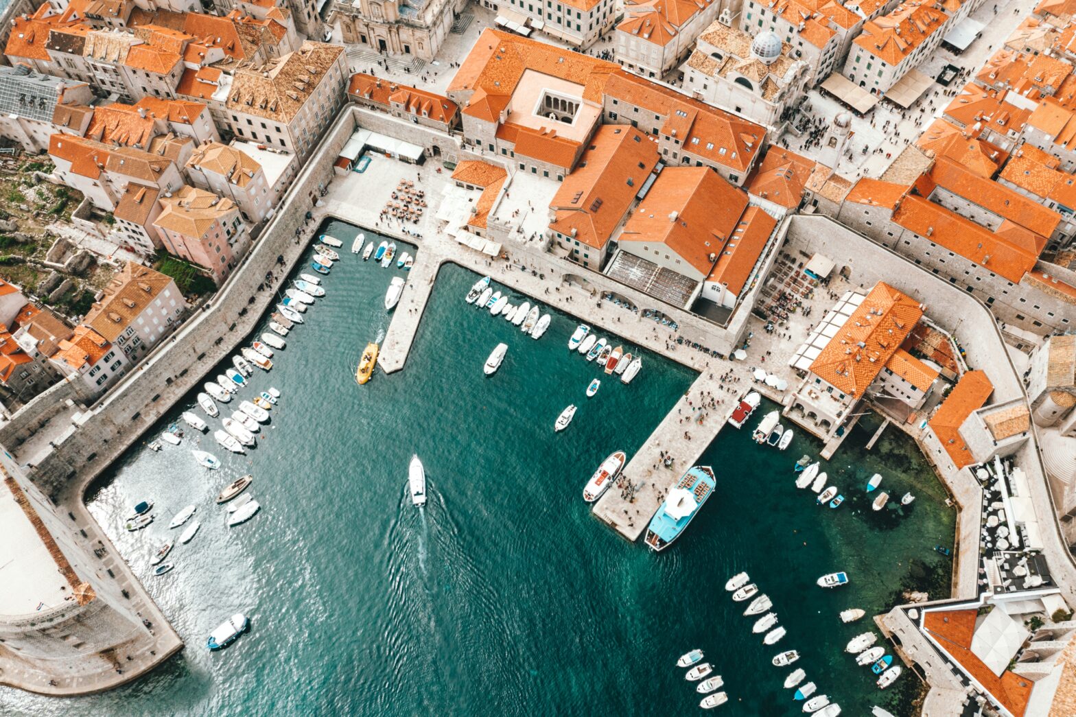 overhead shot of colorful orange rooftops and deep blue green sea in Dubrovnik, Croatia