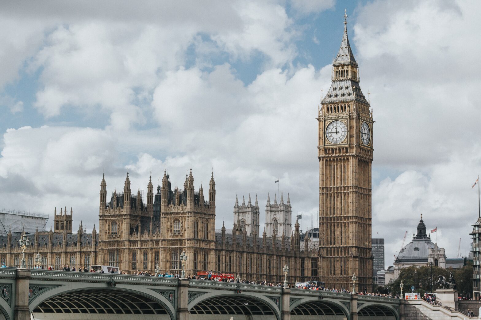 cars driving over bridge leading to Big Ben and the Houses of Parliament in London, England