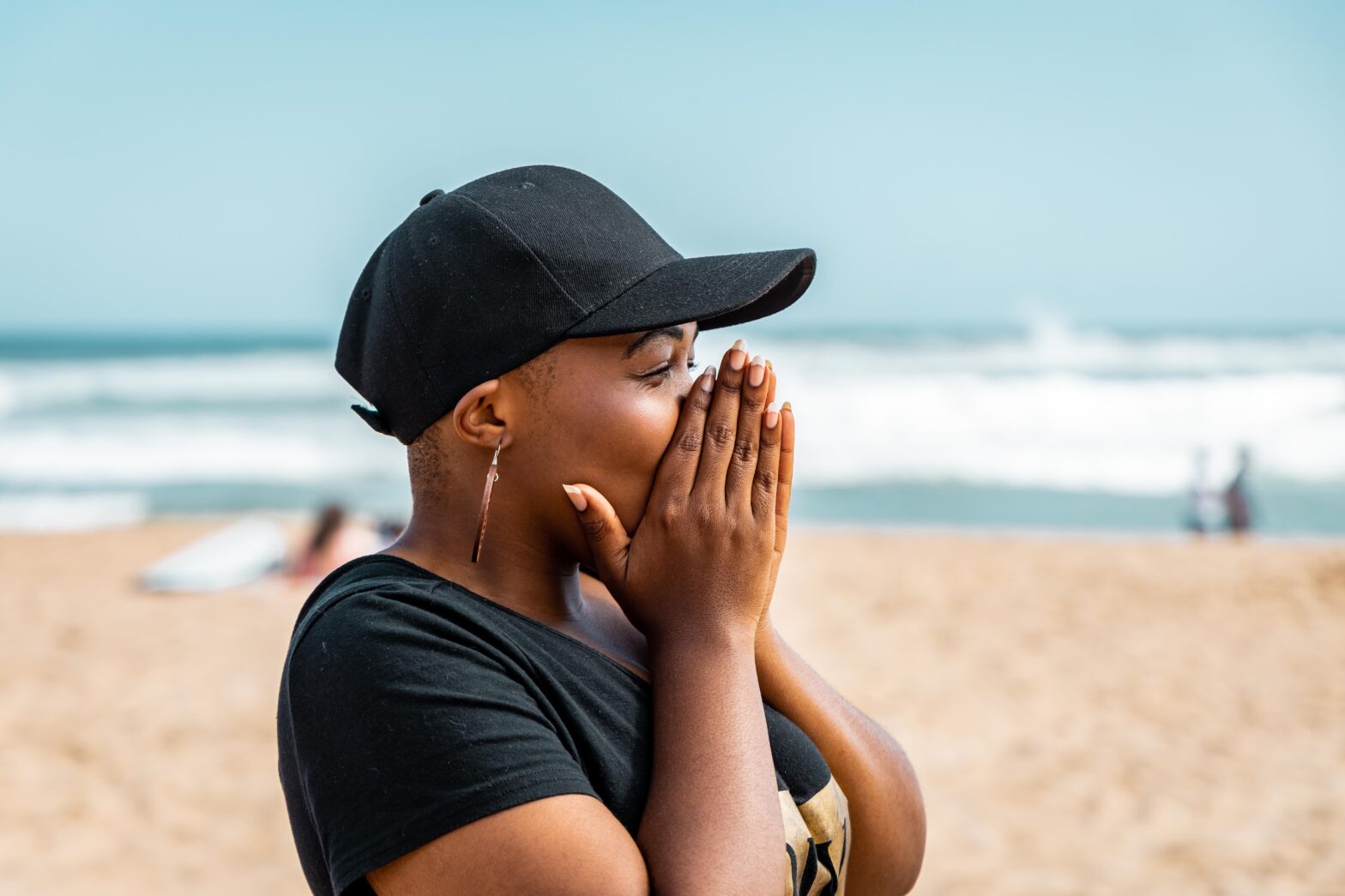 woman with hands over mouth on the beach