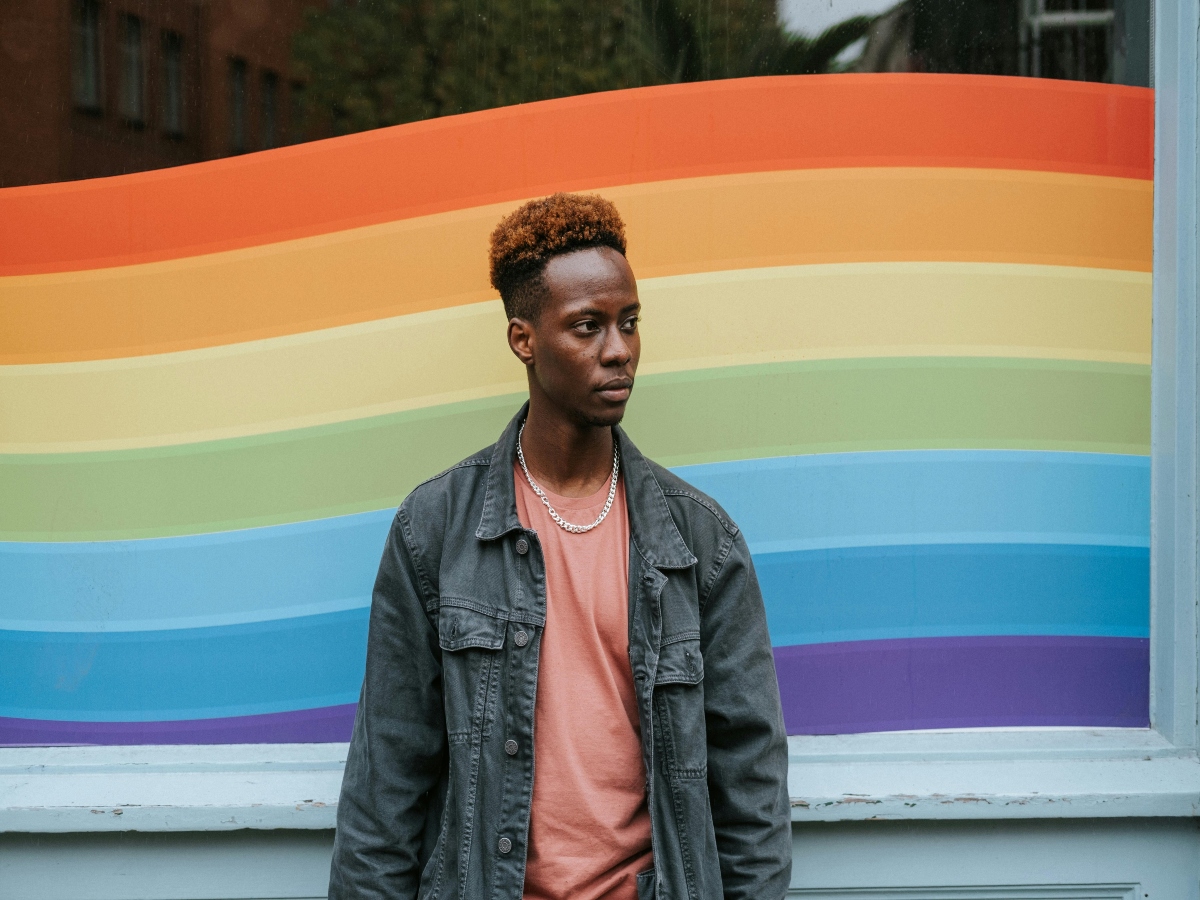 man standing in front of a rainbow mural