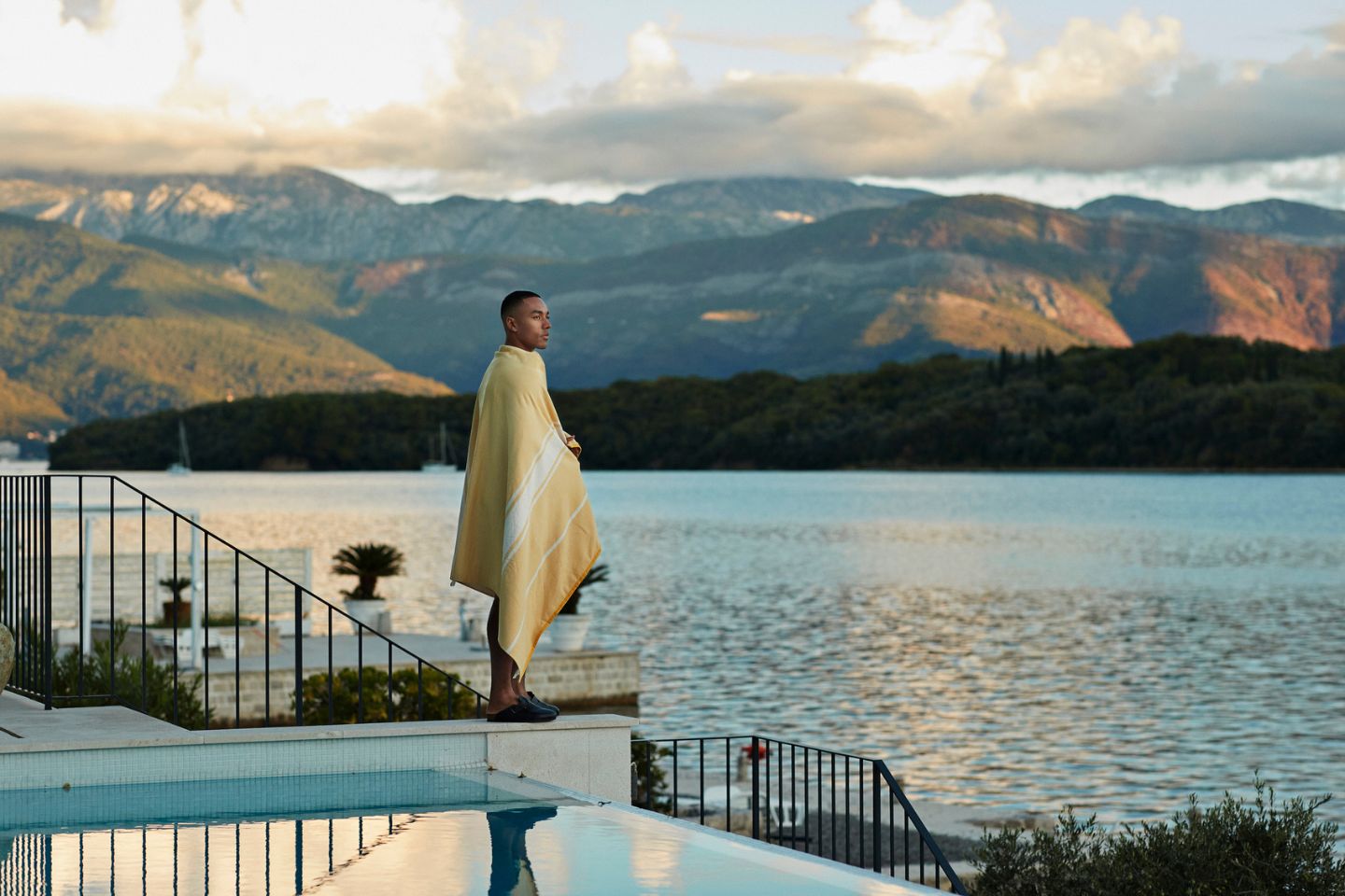 man wrapped in blanket overlooking body of water