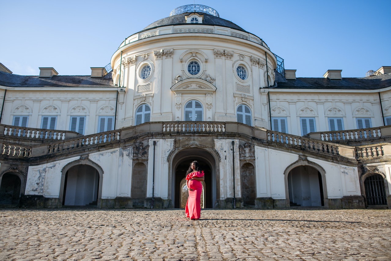 Here are some of the best babymoon destinations. Pictured: pregnant woman outside of European building.