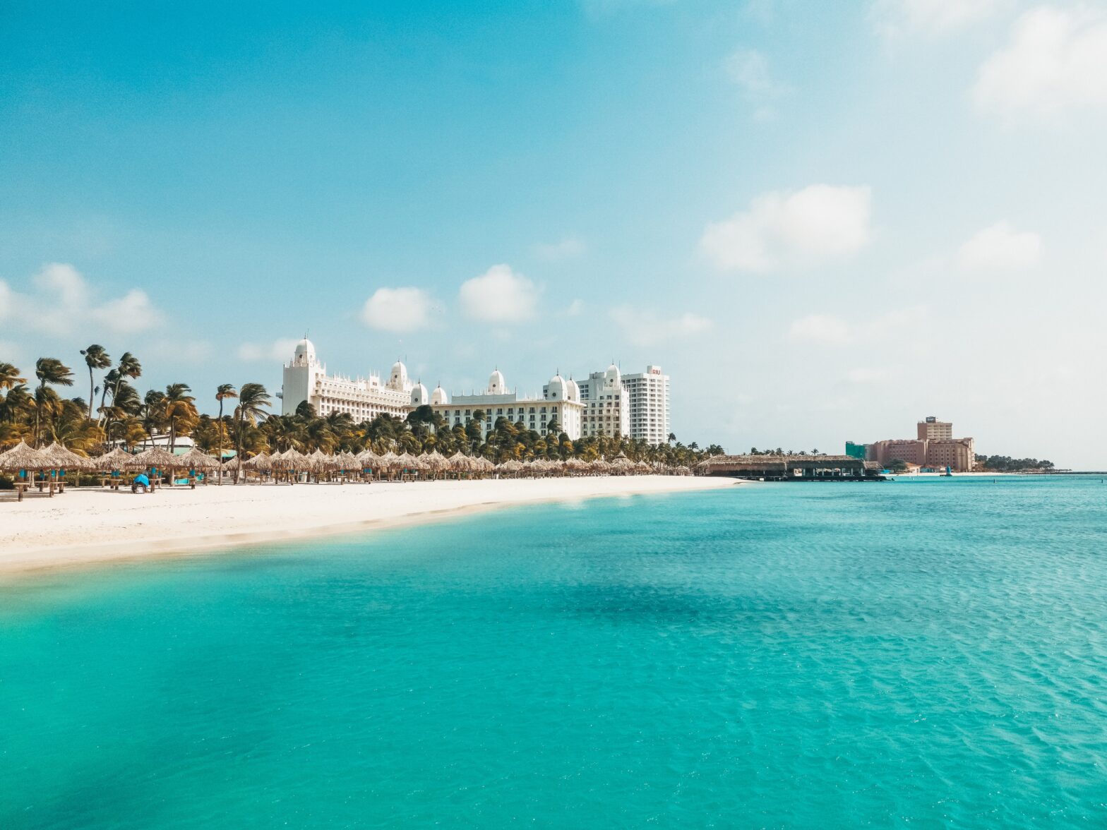 Learn more about Aruba and its safety levels for tourists. pictured: distant resorts nearby the Aruba beach with clear waters and white sands