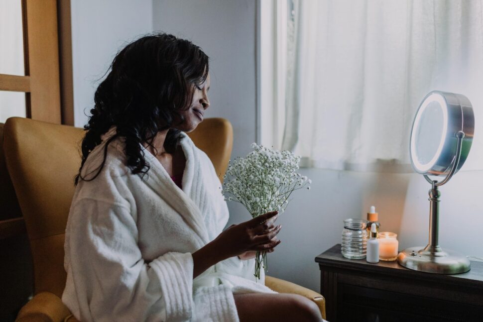 A Woman Wearing White Robe Holding a Bunch of Baby's Breath Flowers