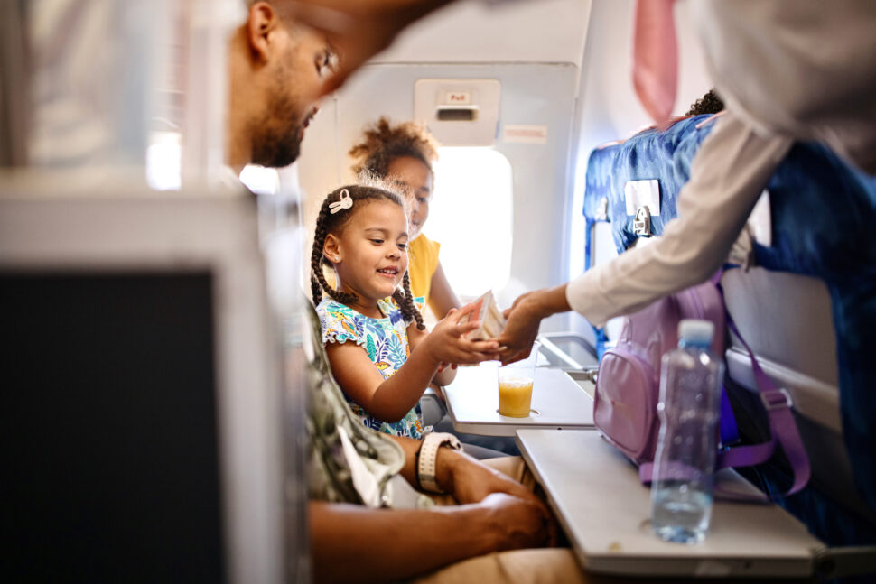 Stewardesses serving food and drinks to family on the airplane during flight